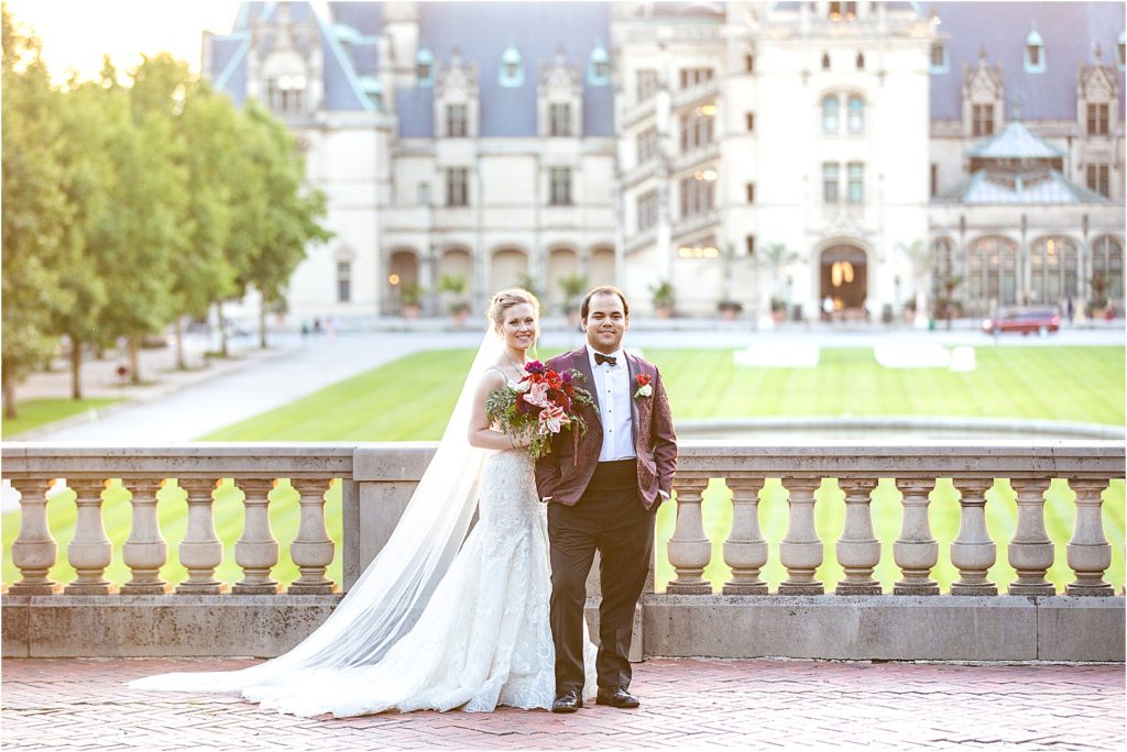 A bride and groom standing in front of the biltmore house