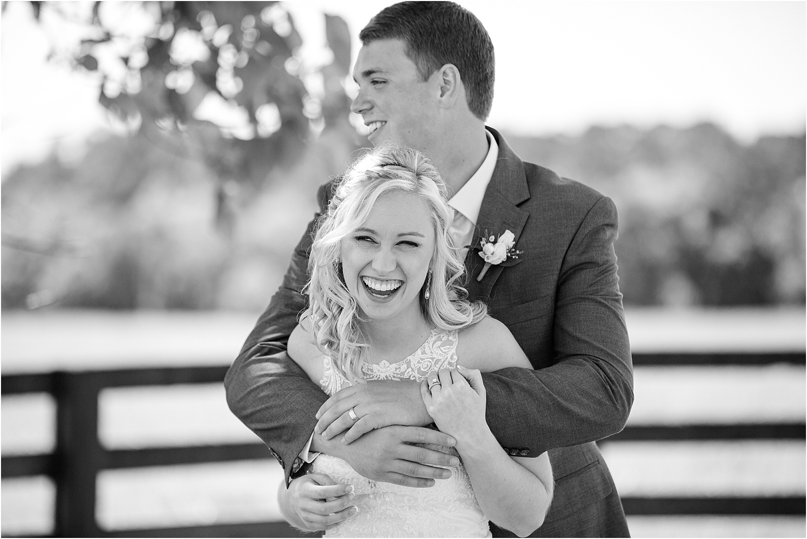 Wife in wedding dress laughs while husband hugs her