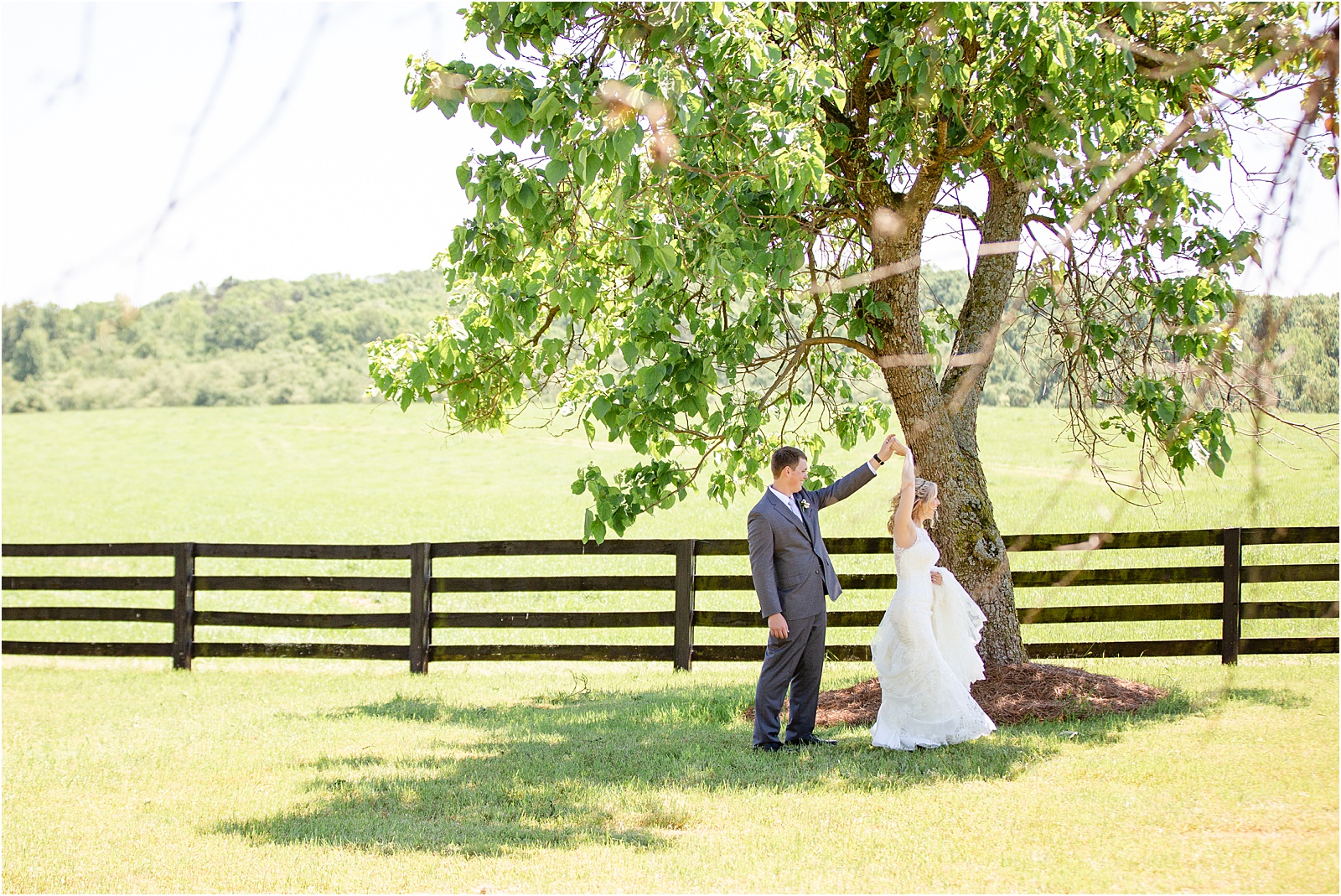 Bride and groom twirl in a field