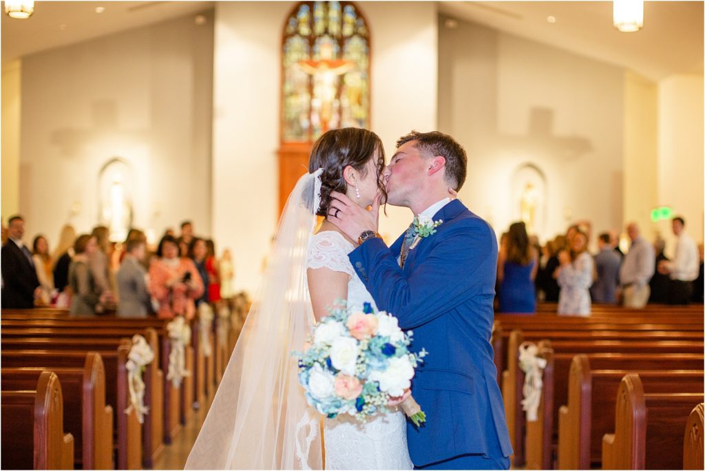 Husband and wife kiss at end of church aisle