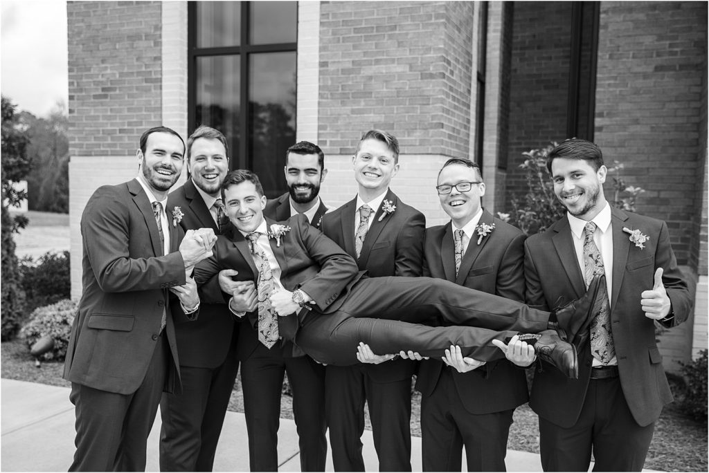 Guys hold groom up for funny pictures