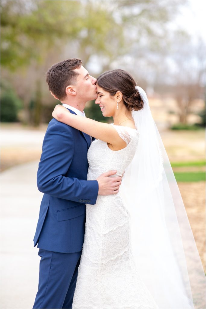 Groom kisses bride's forehead for wedding pictures