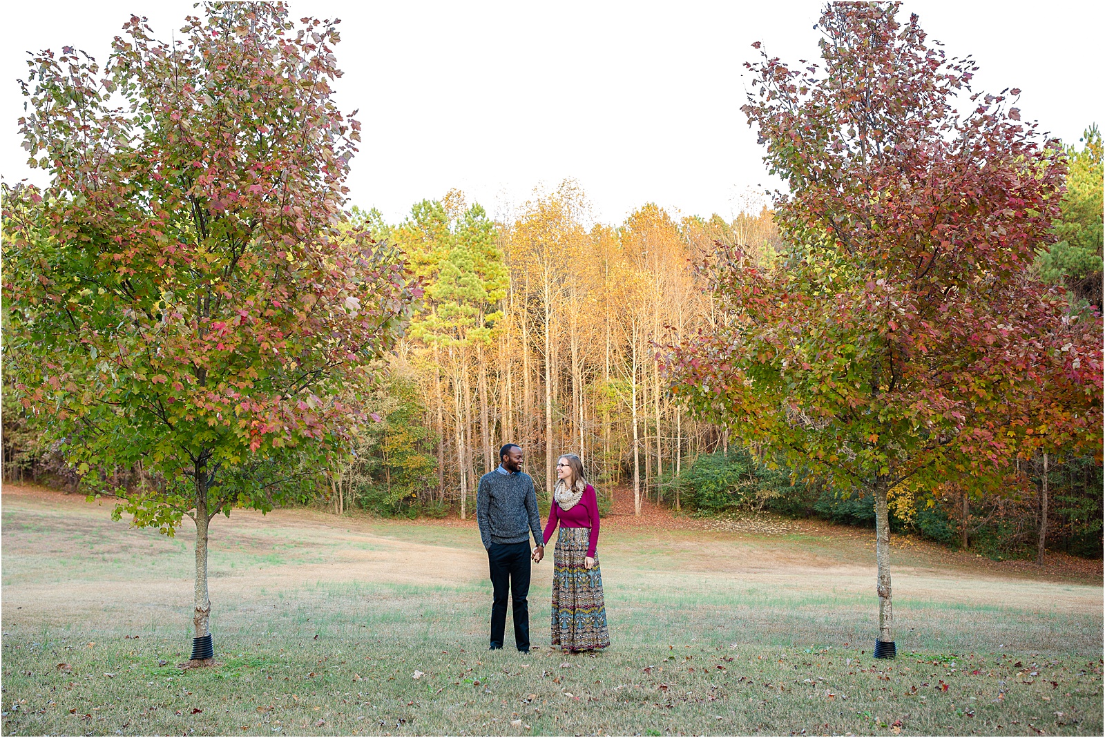 Couple posing for pictures between trees