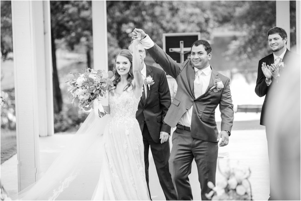 Groom holds up hands after wedding
