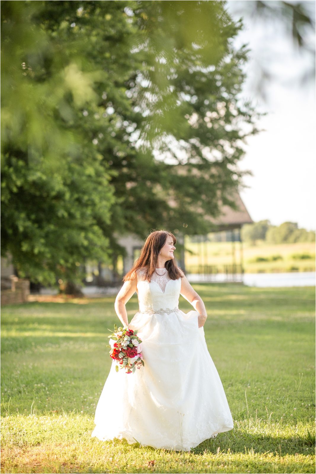Wedding bride walking with dress in hands in field