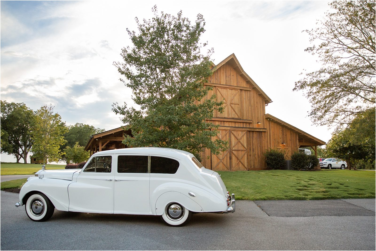 White Rolls Royce in front of barn wedding venue