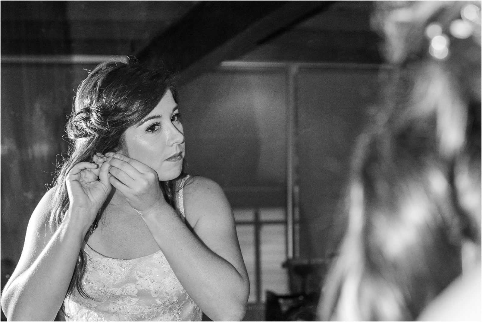 Bride looks in mirror as she puts on earrings