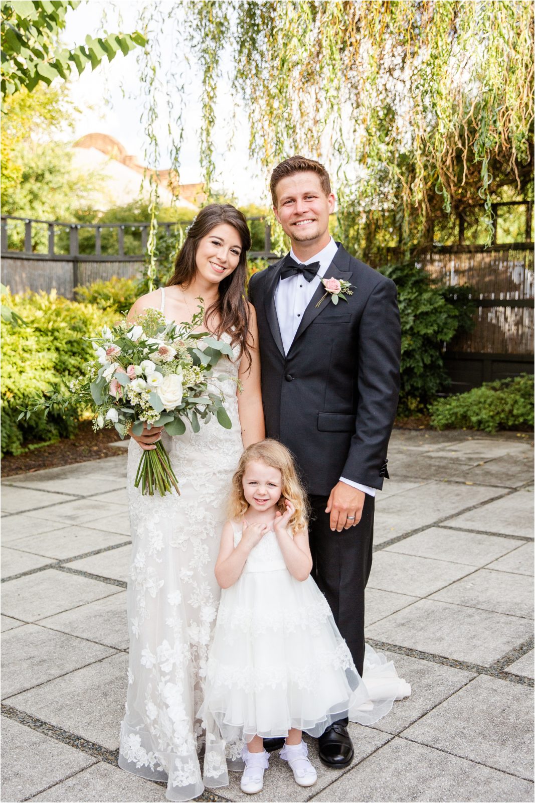 Groom and bride stand with flower girl