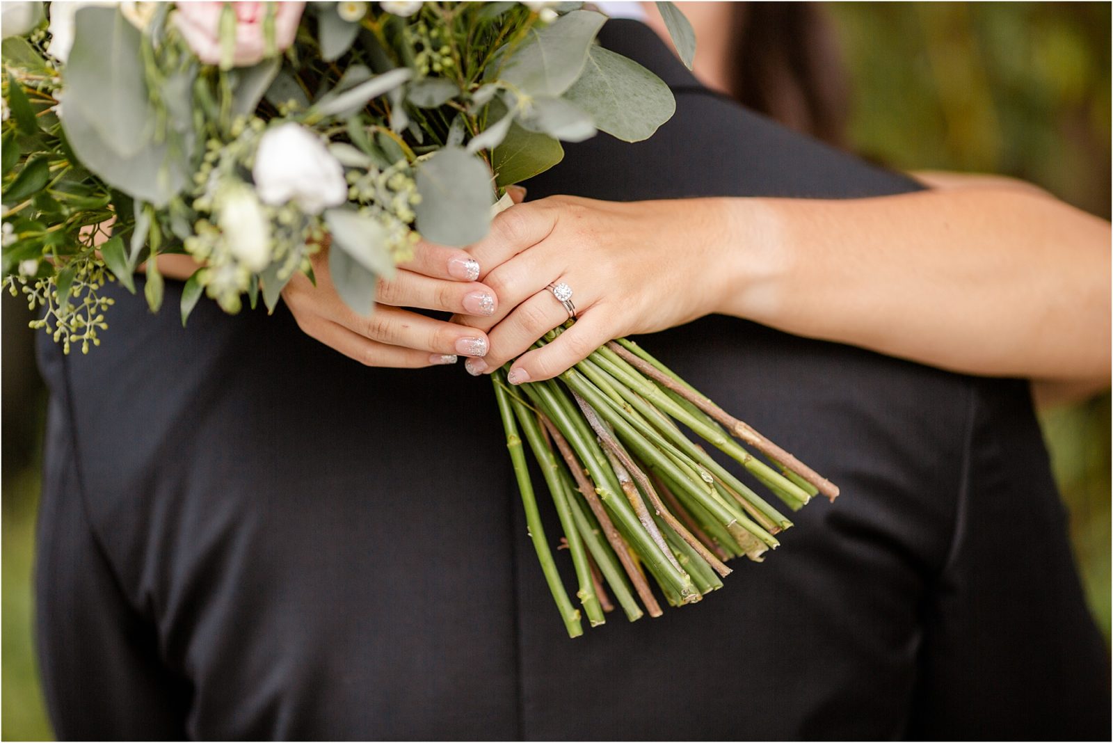 Bride holds flowers around groom's neck