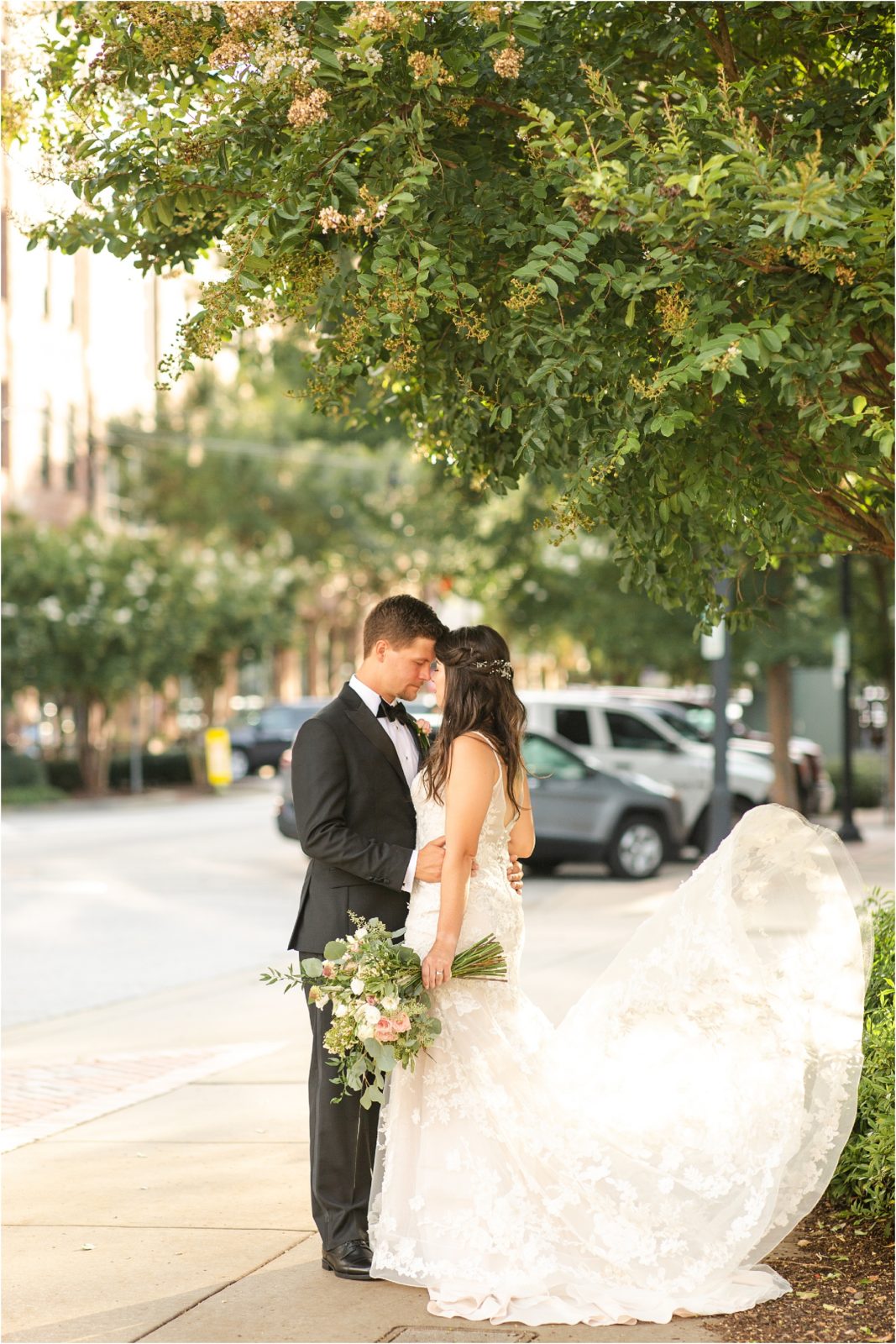 Man in tux and woman in wedding gown standing in Downtown Greenville