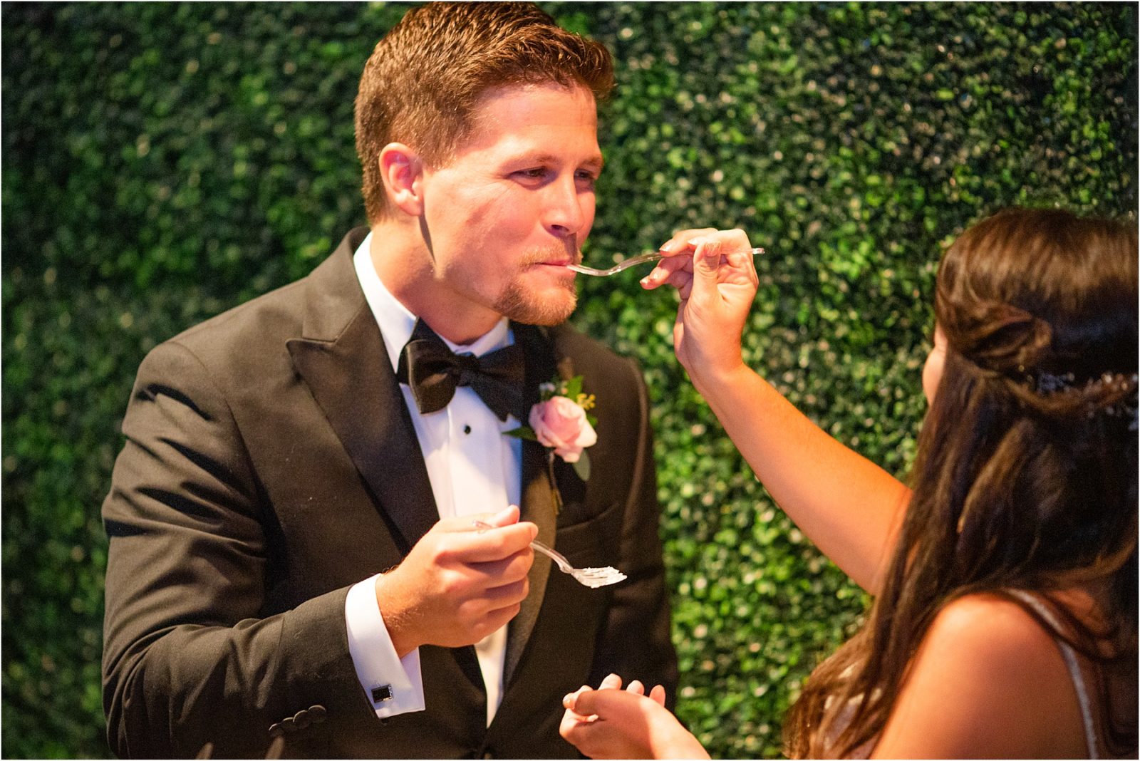 Groom smiling as his new bride feeds him cake