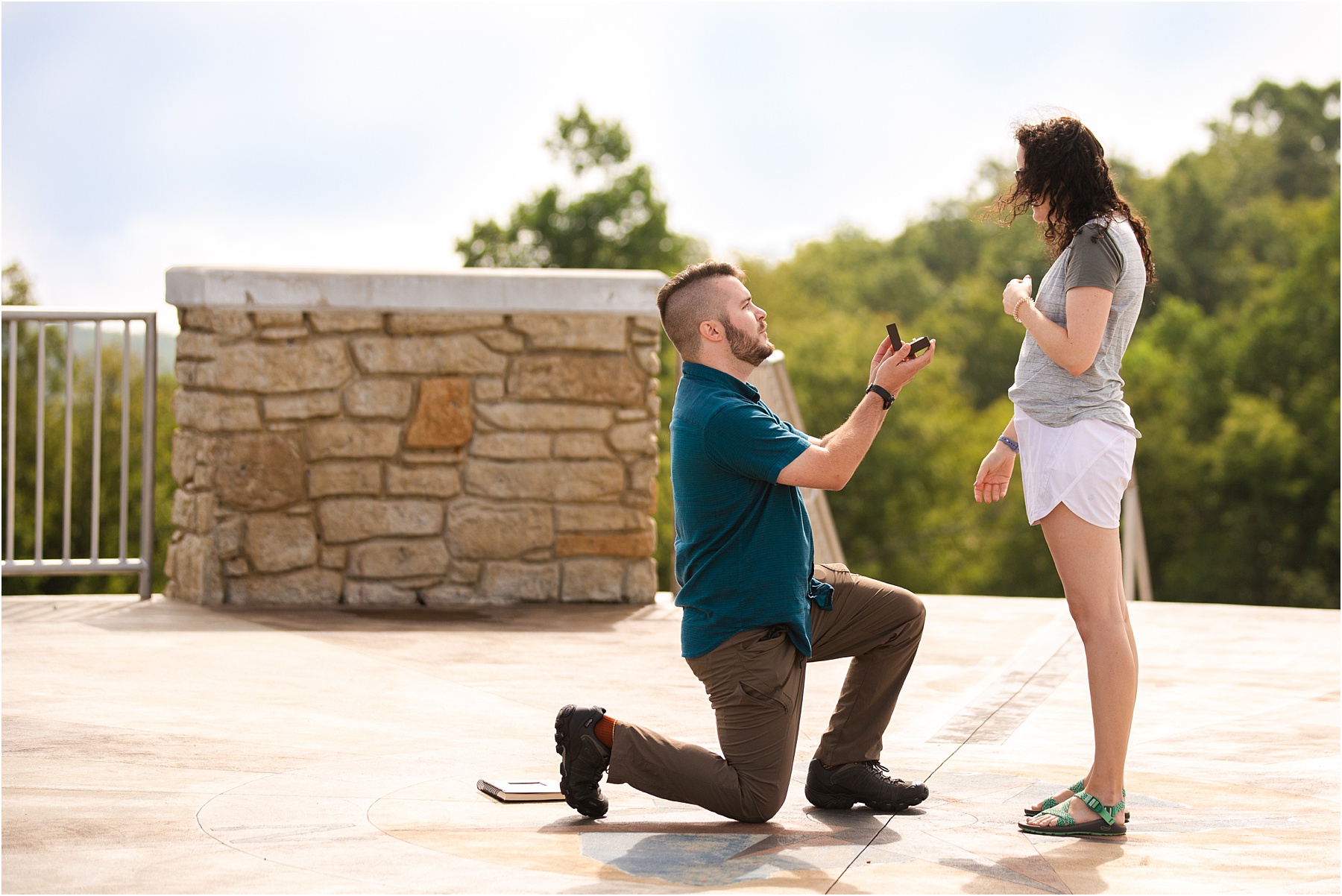 Man on one knee proposing to woman on mountain top