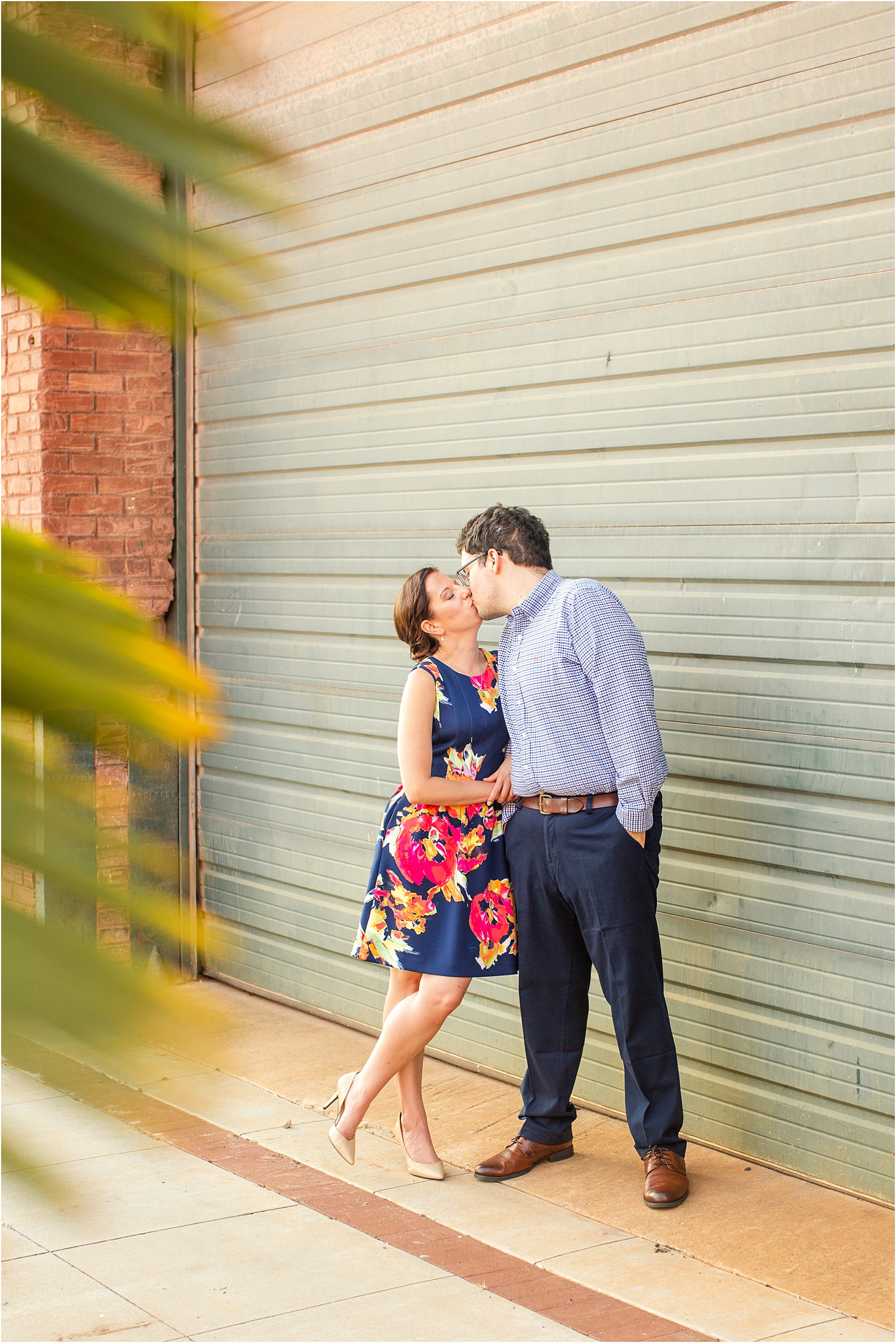 Engaged couple kissing in front of Anderson SC building