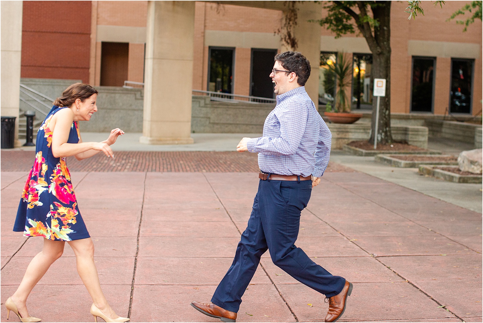 Woman laughing as guy runs towards her for engagement pictures