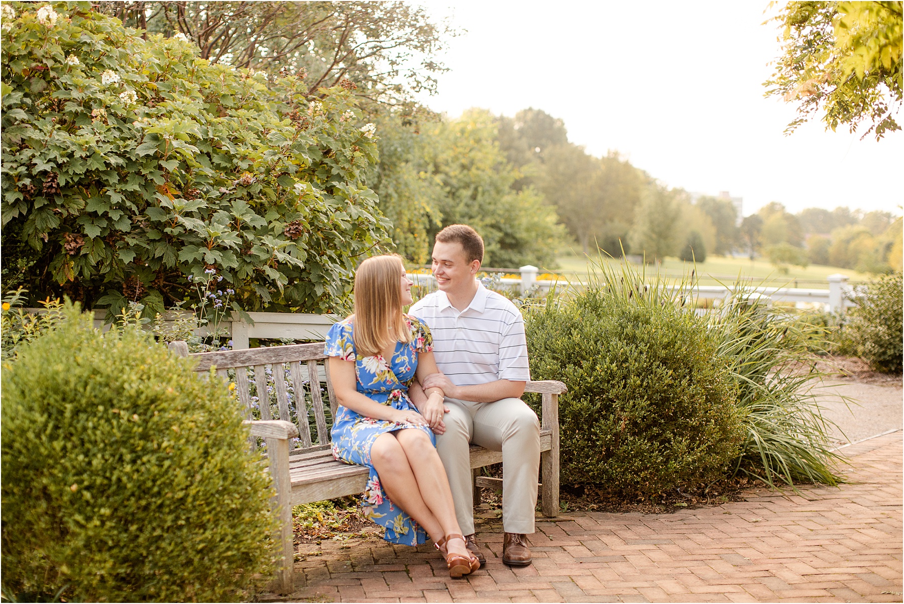 Engaged couple sitting on park bench in Kentucky botanical gardens