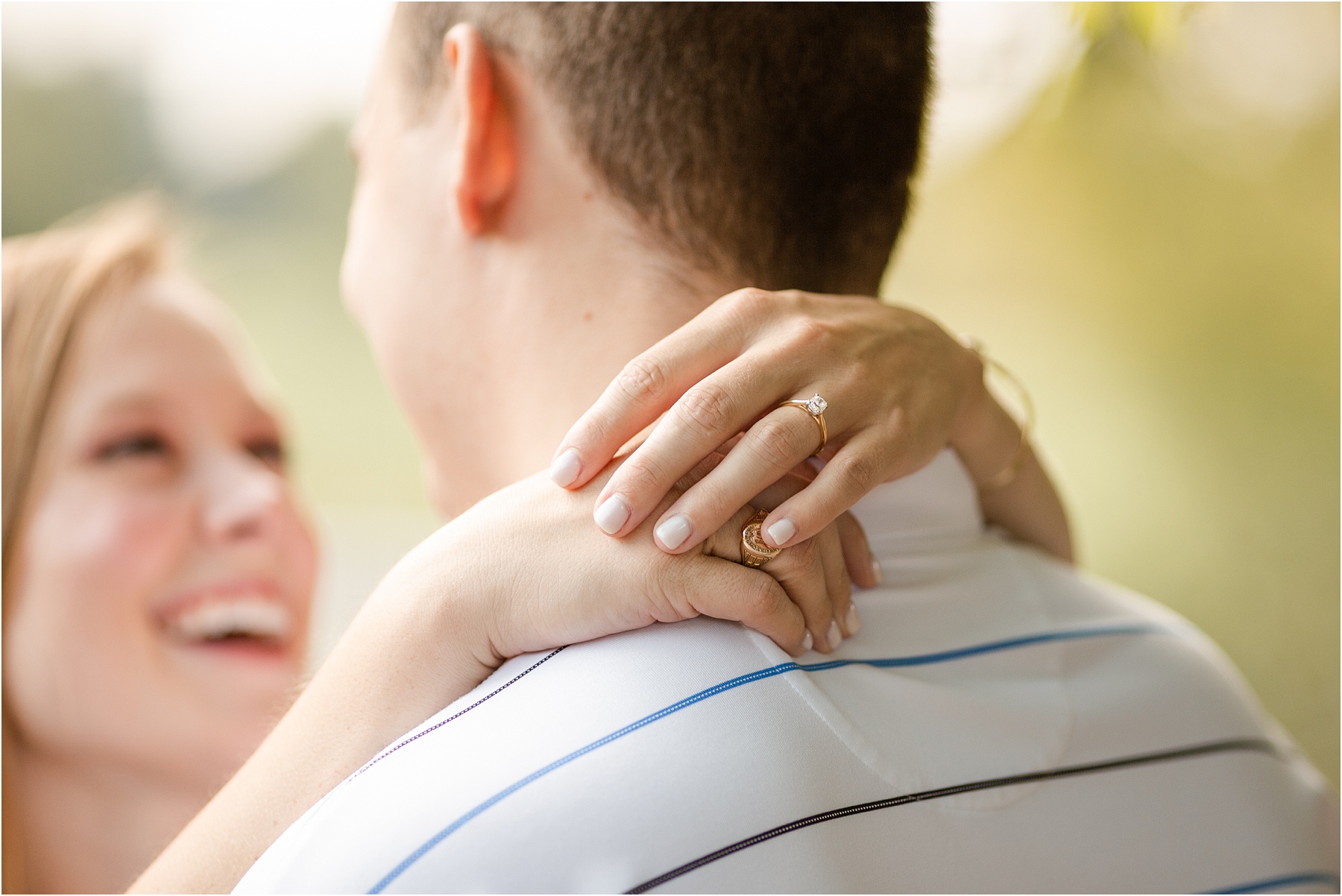 Woman laughing with hands around her fiance's neck with engagement ring