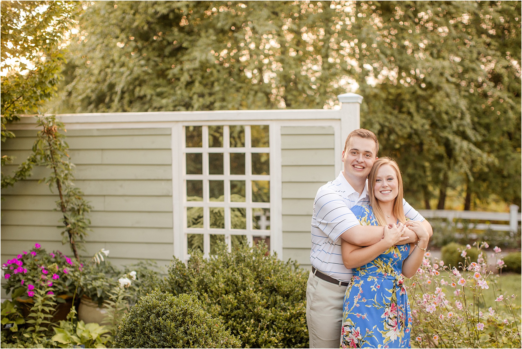 Guy has arms around fiance in garden