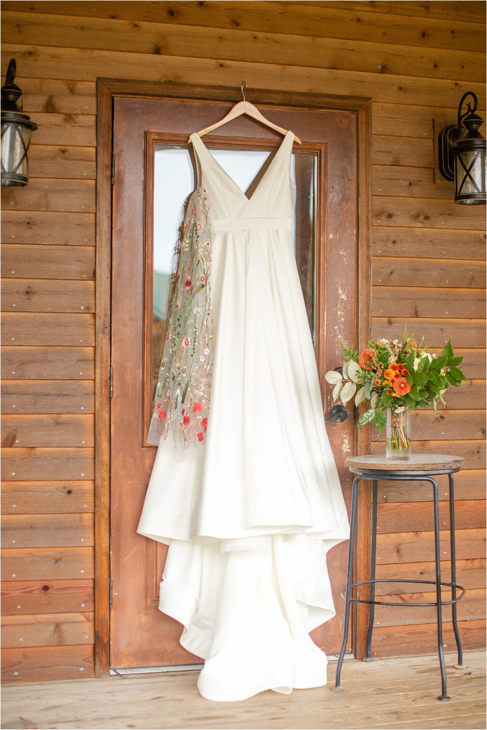 White wedding dress and floral veil hanging on barn wall in Greenville