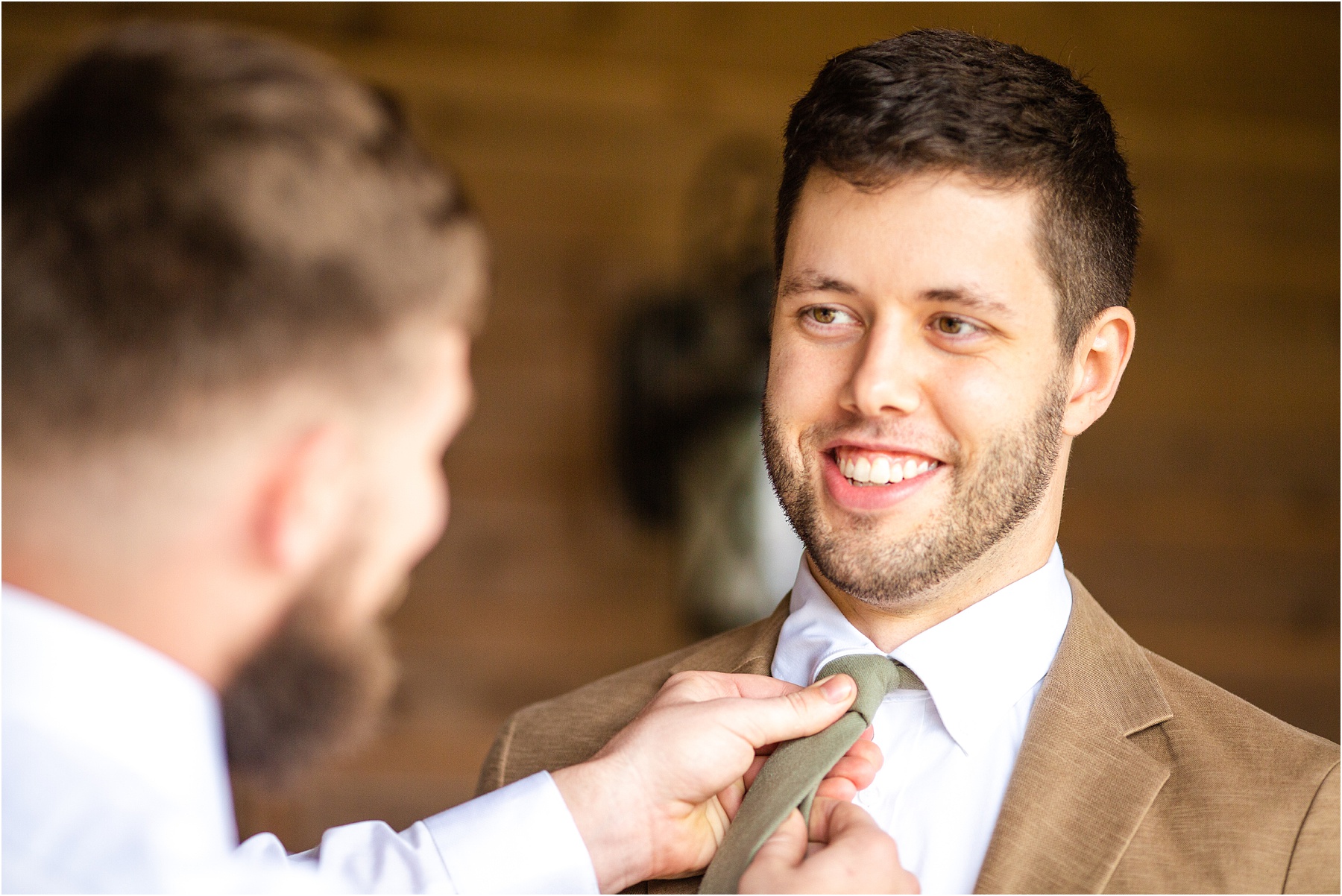 Friend straightening tie of groom