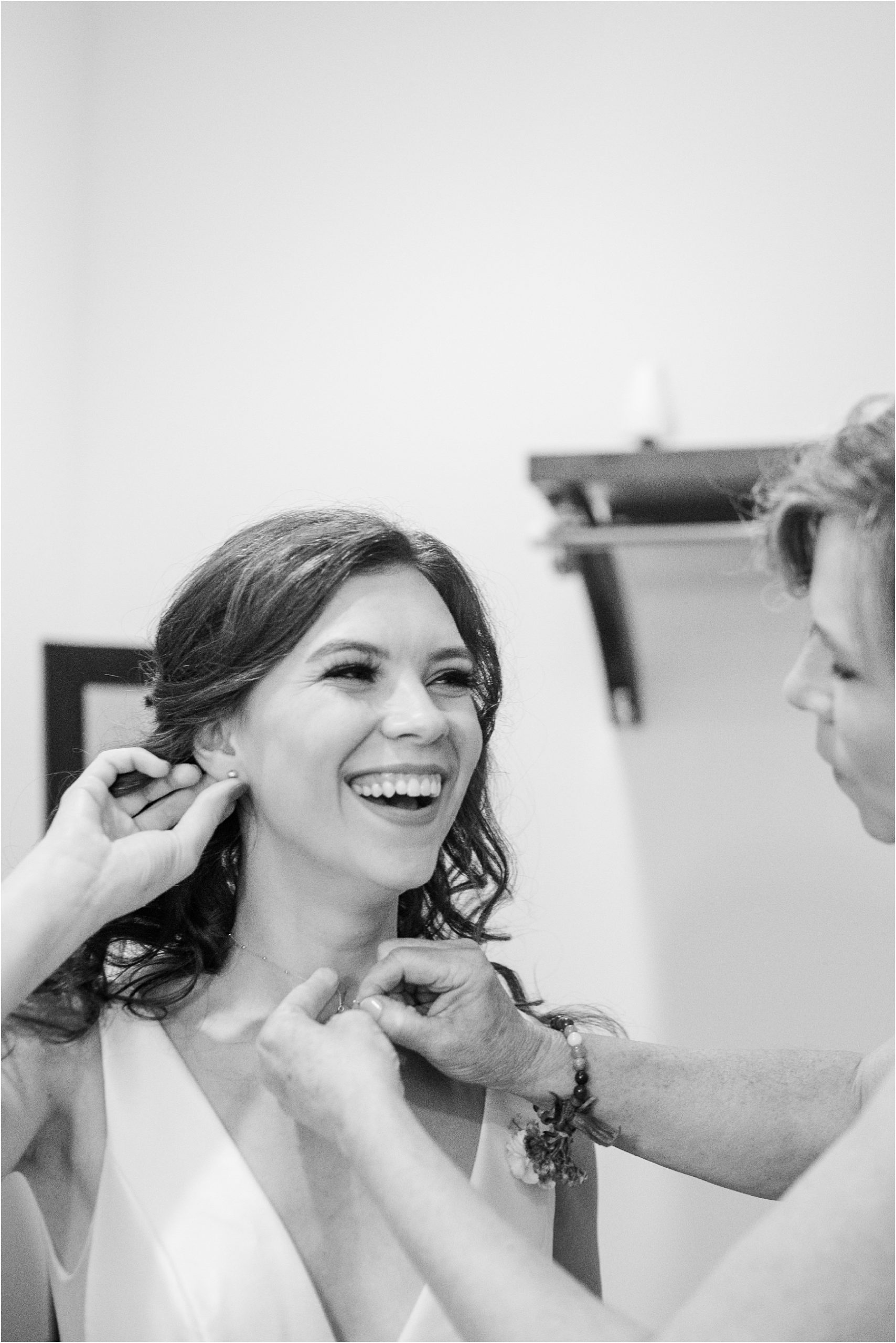 Woman laughing as she puts on earrings for her wedding