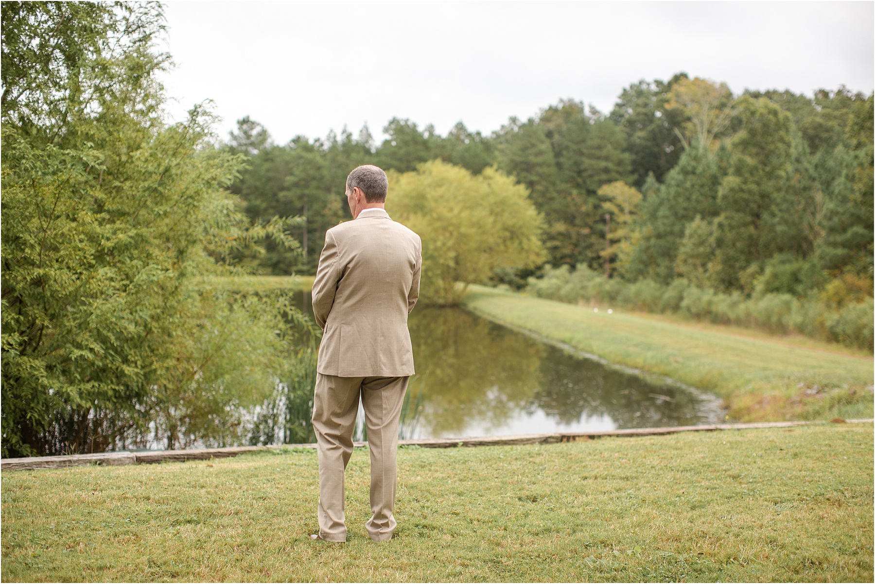 Man in wedding suit looking at pond in Greenville Mountain Vineyard before wedding