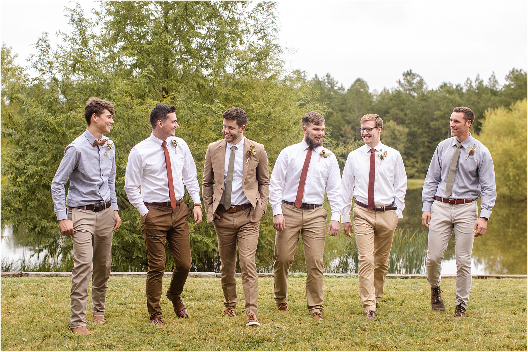 Groom walks with his groomsmen in front of a pond