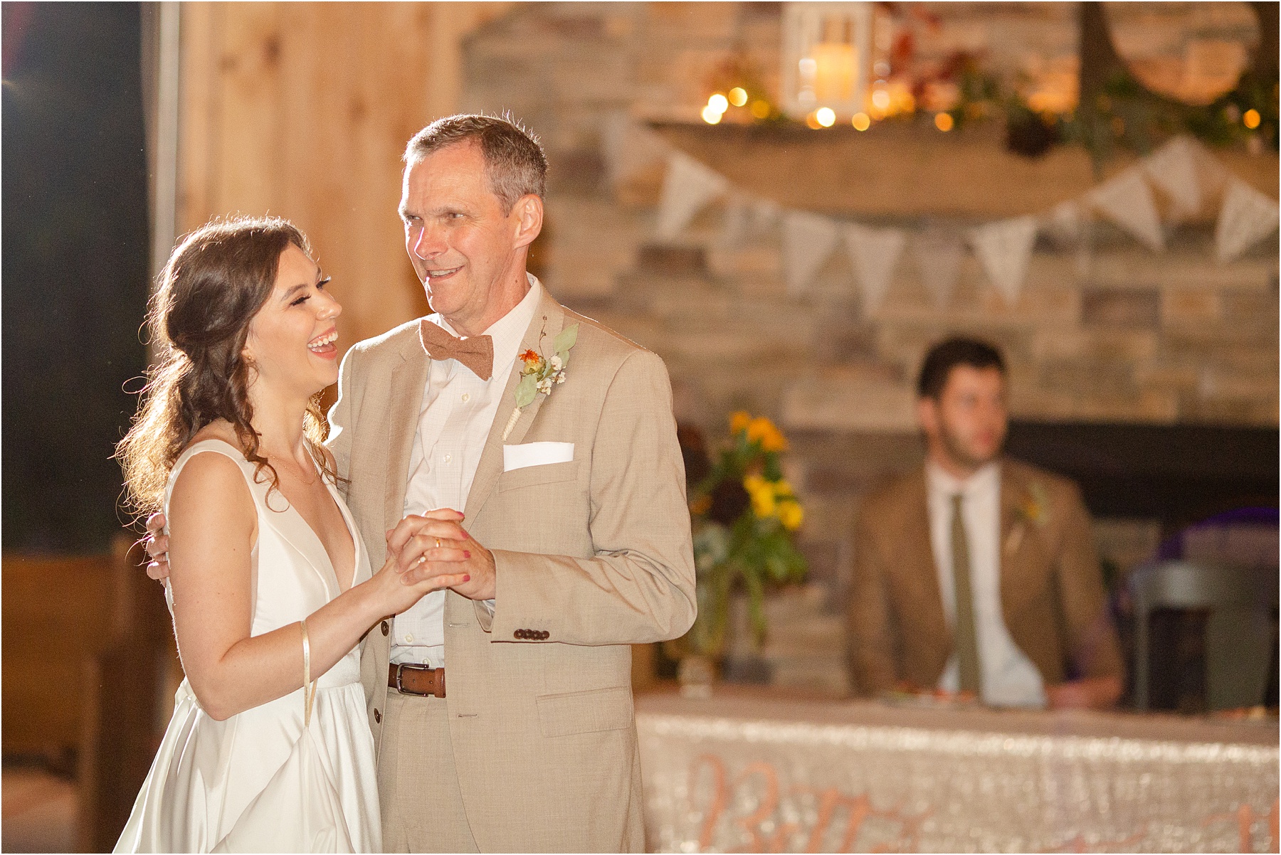 Dad in tan suit dancing with his daughter in a wedding dress