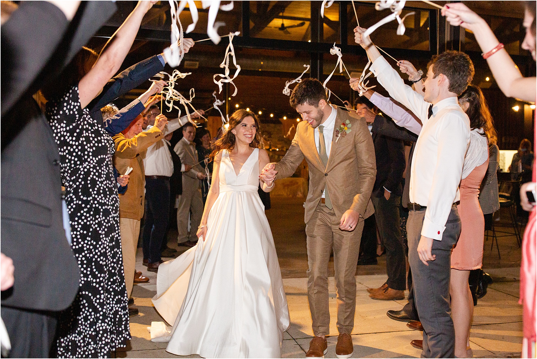 Couple walking through streamers as they leave wedding reception