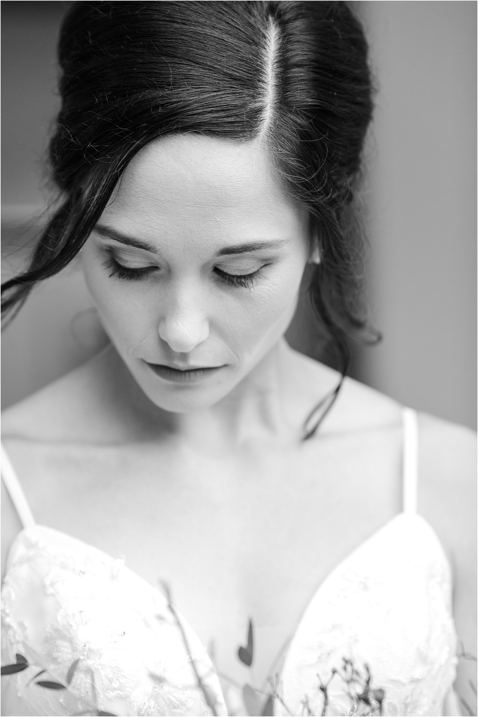 black and white portrait of a brunette bride looking down at her bouquet