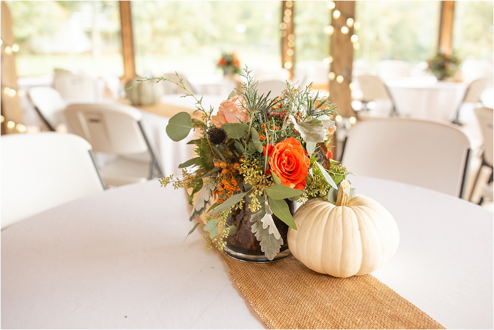 flowers and a white pumpkin on a wedding reception table