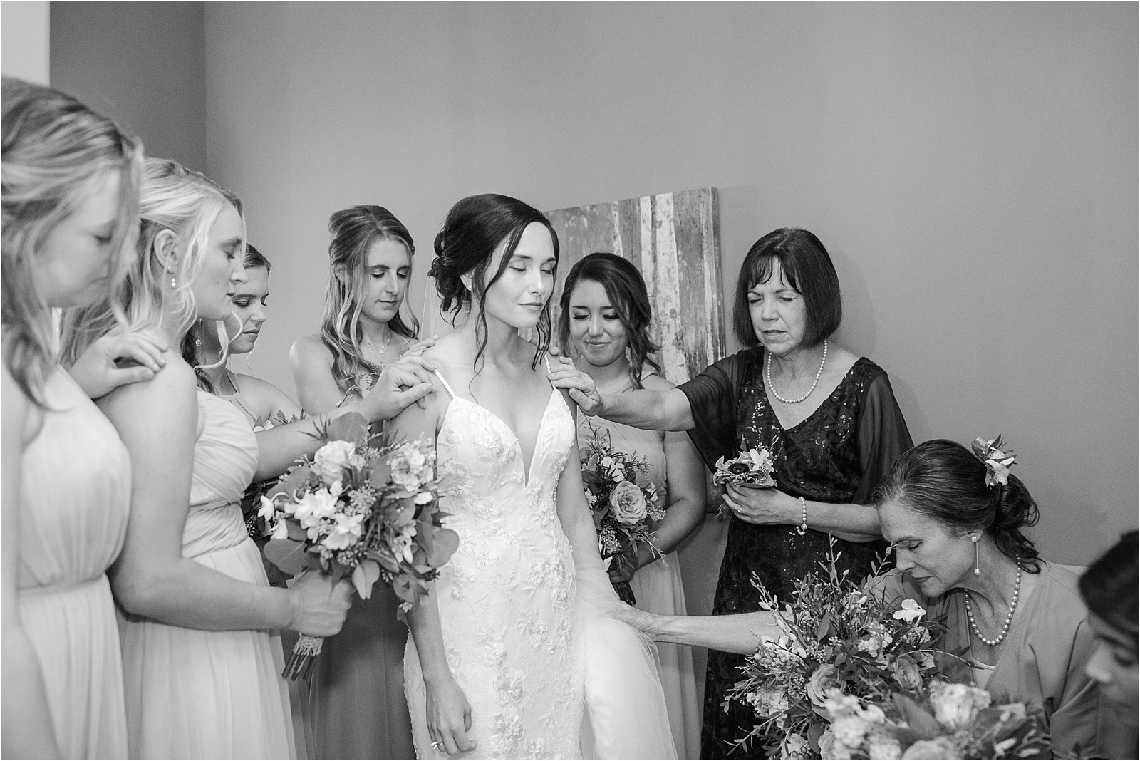 woman in wedding dress being prayed over by her friends