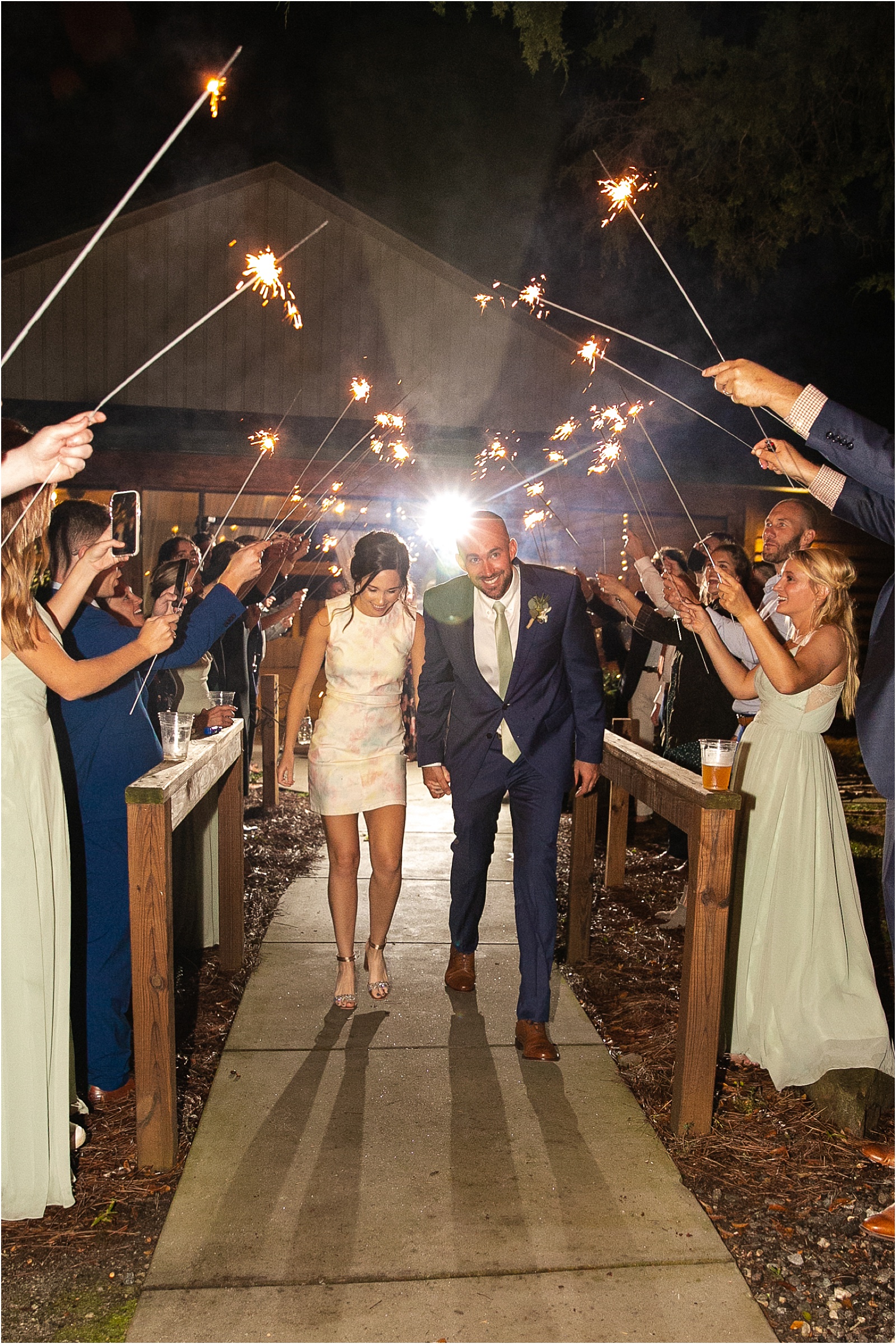 Bride and groom leaving barn wedding venue through sparklers