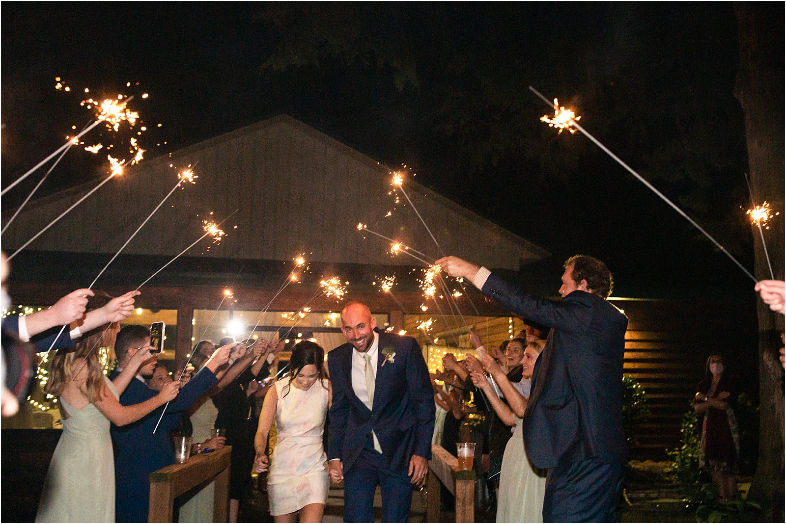 Wedding guests holding up sparklers as bride and groom walk through