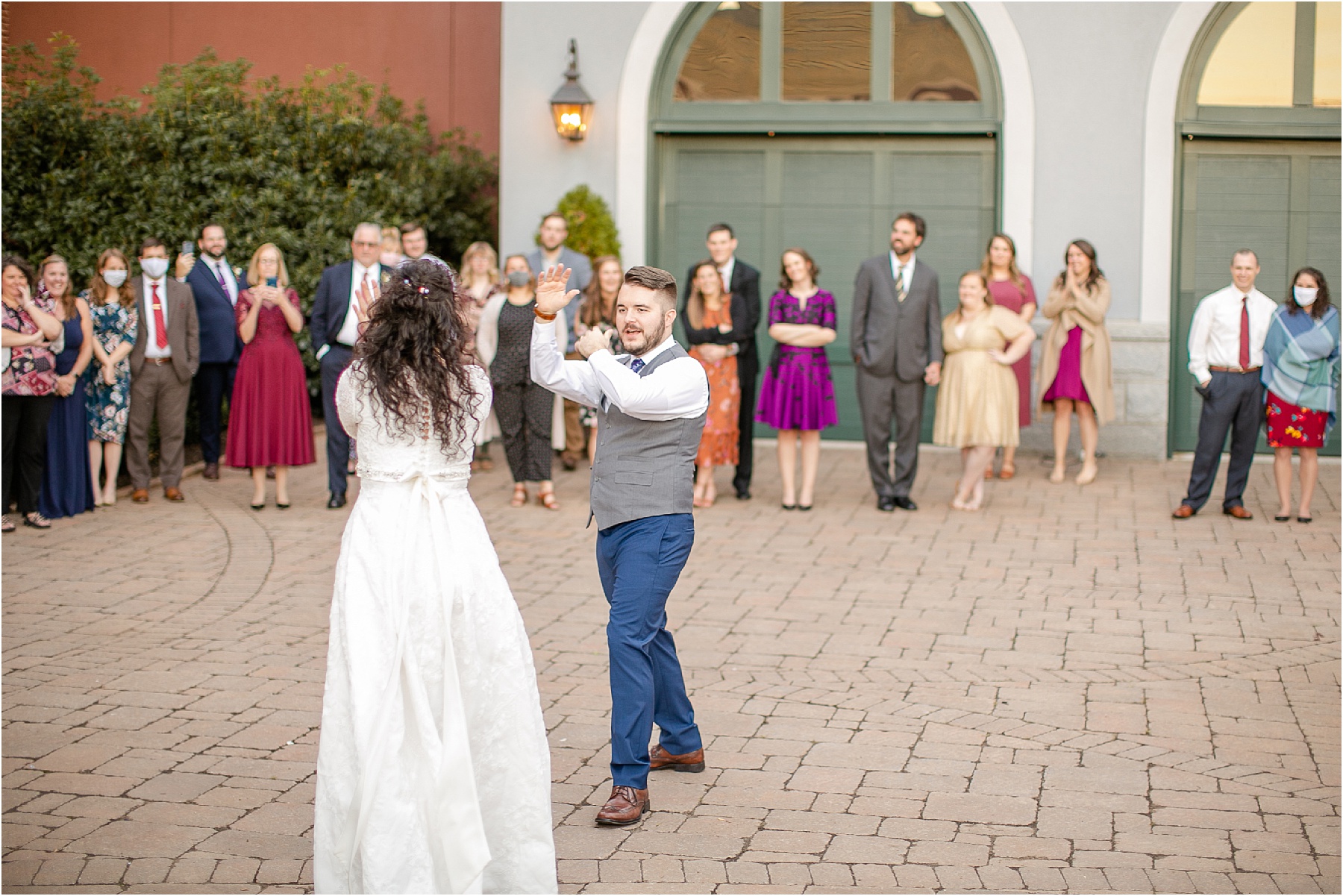 groom in gray vest and blue pants dances with bride
