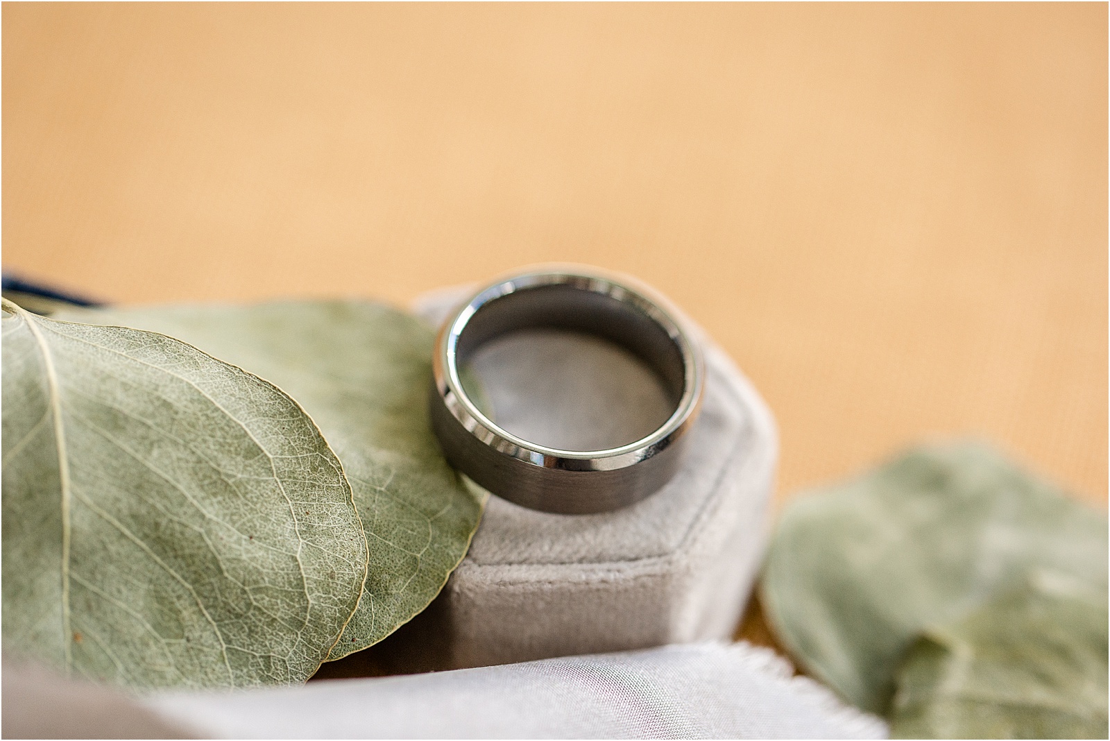 man's wedding ring on a ring box with leaves