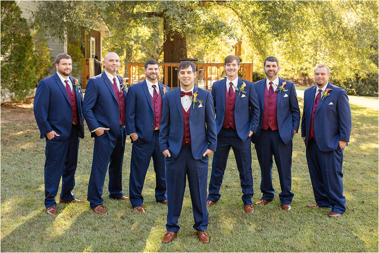 Group of men dressed for wedding with red vests and hands in pockets