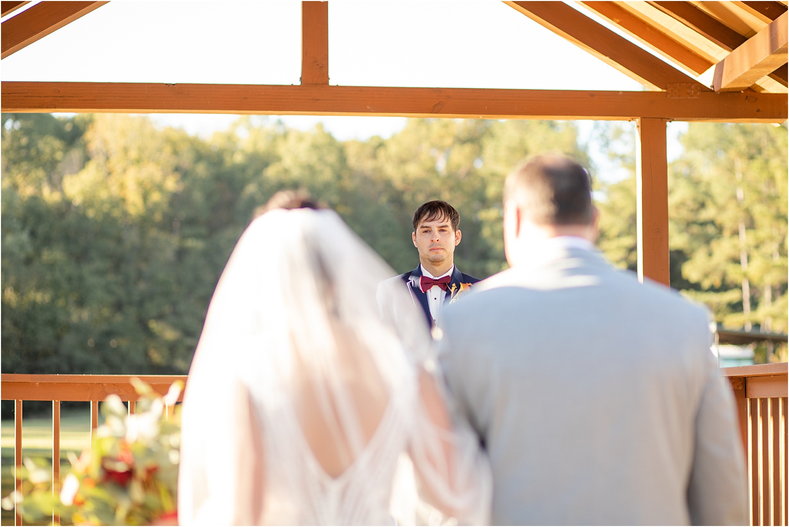 Groom looks at his bride as she walks down the aisle with her father