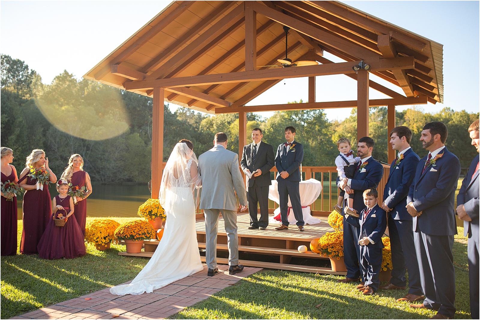 Father of the bride gives away bride to groom in outdoor ceremony