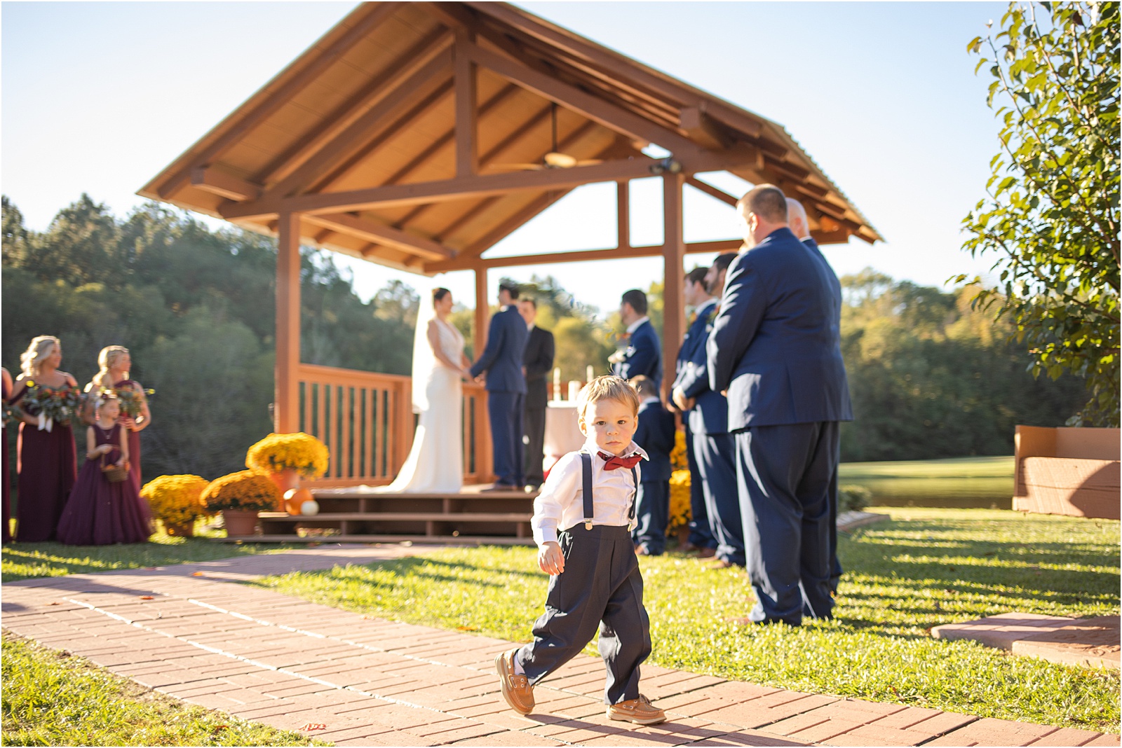 small boy in bow tie walking around at wedding ceremony