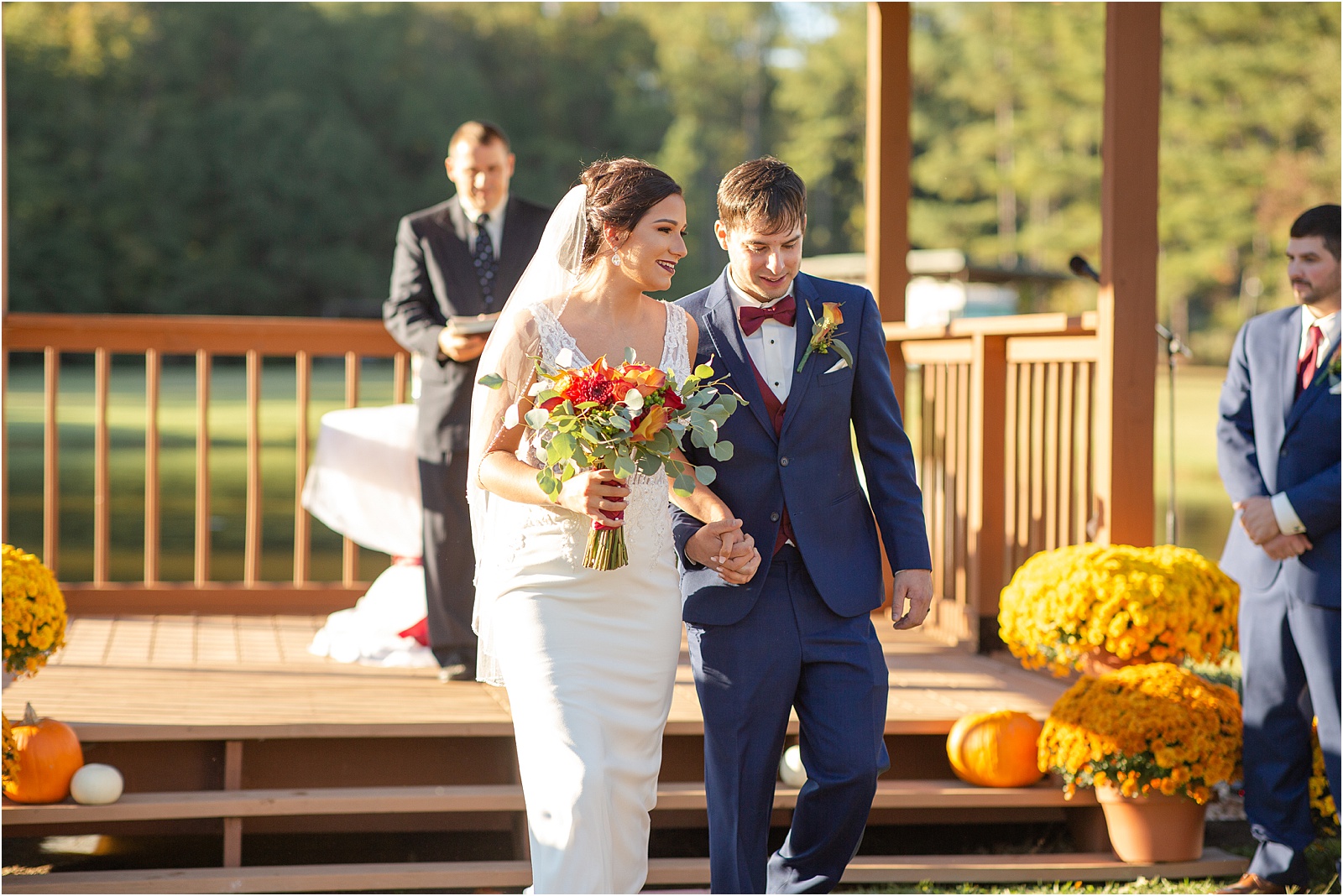 Just married couples holds hands while walking down the aisle from outdoor wedding venue