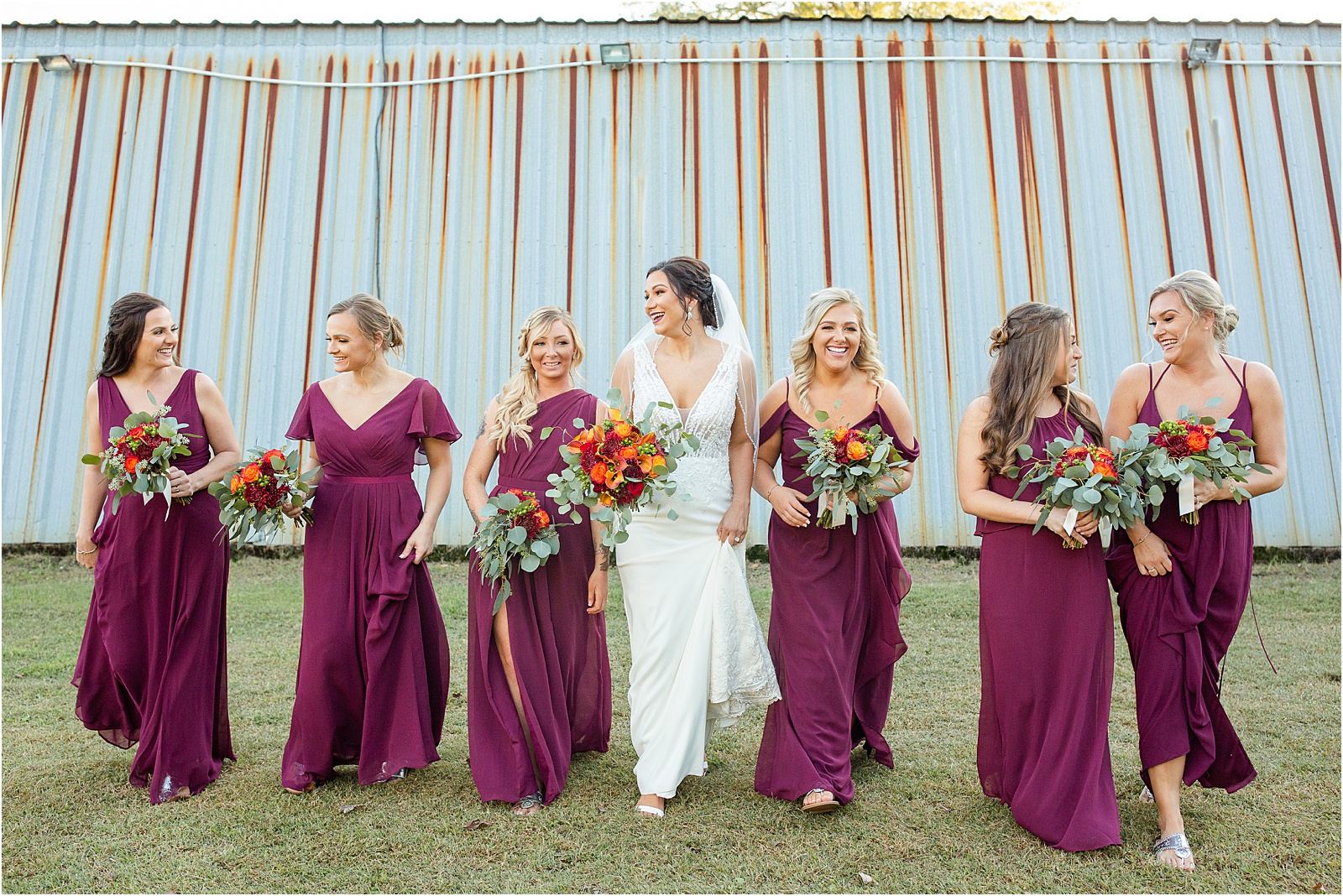 woman in wedding dress walks with bridesmaids in violet dresses