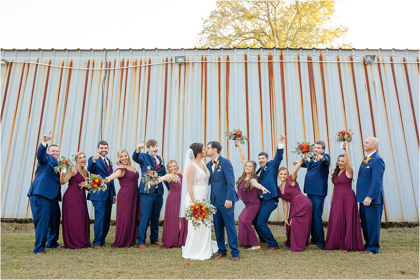 groomsmen and bridesmaids celebrating while bride and groom share a kiss