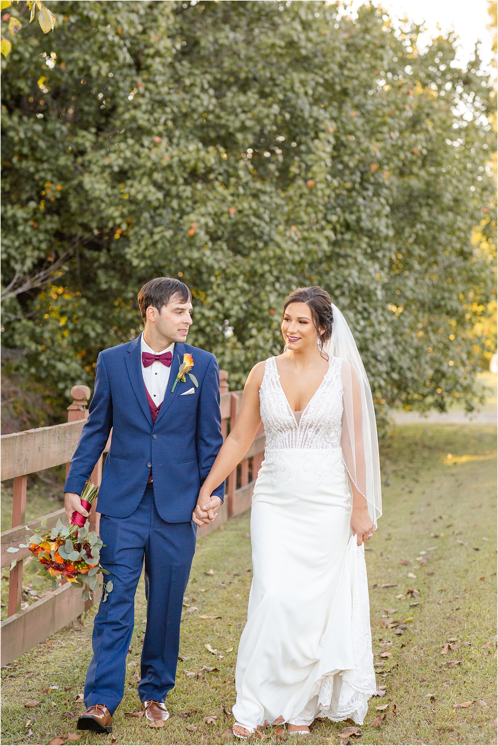 Groom and bride walk by wooden fence after wedding in Columbia, SC
