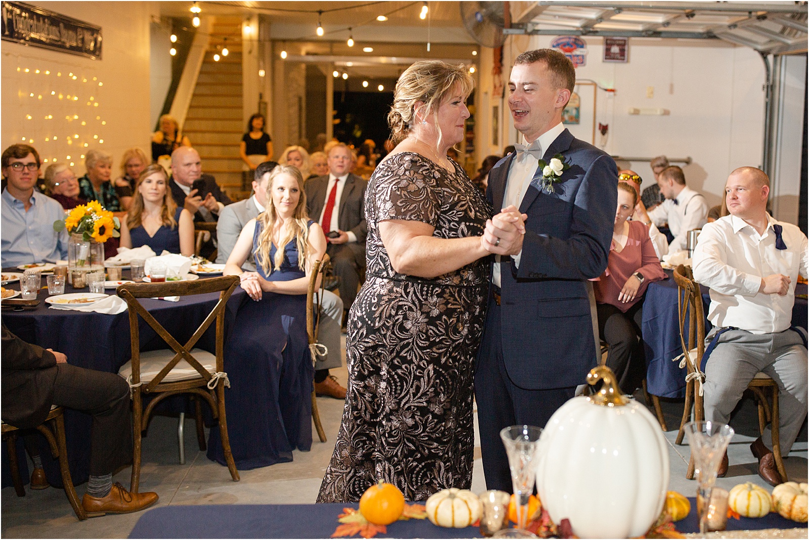 groom dances with his mother at wedding reception decorated with pumpkins