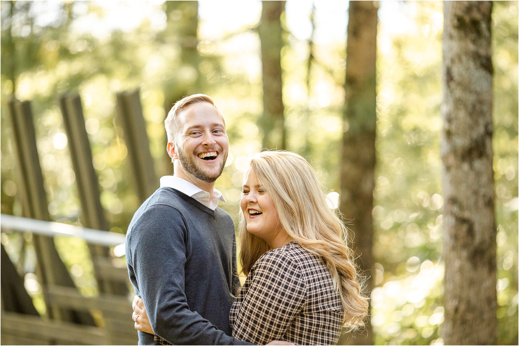Guy and girl laughing in the woods dressed for engagement pictures