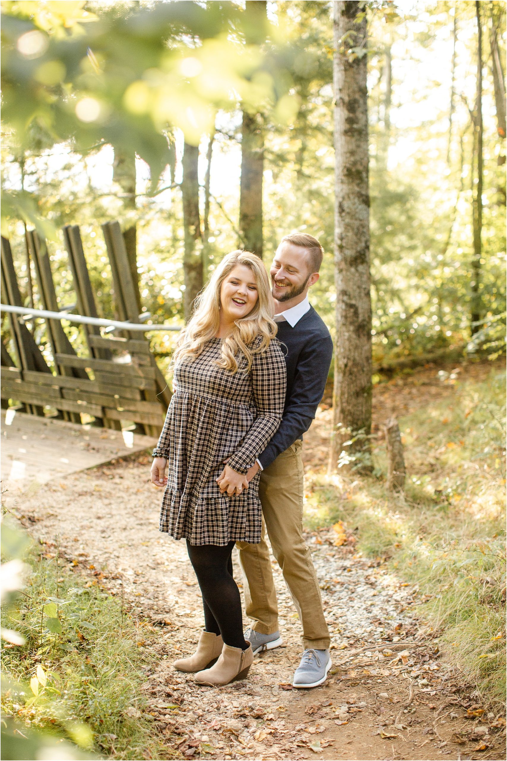Woman laughing with her fiancé as they hold hands in the woods