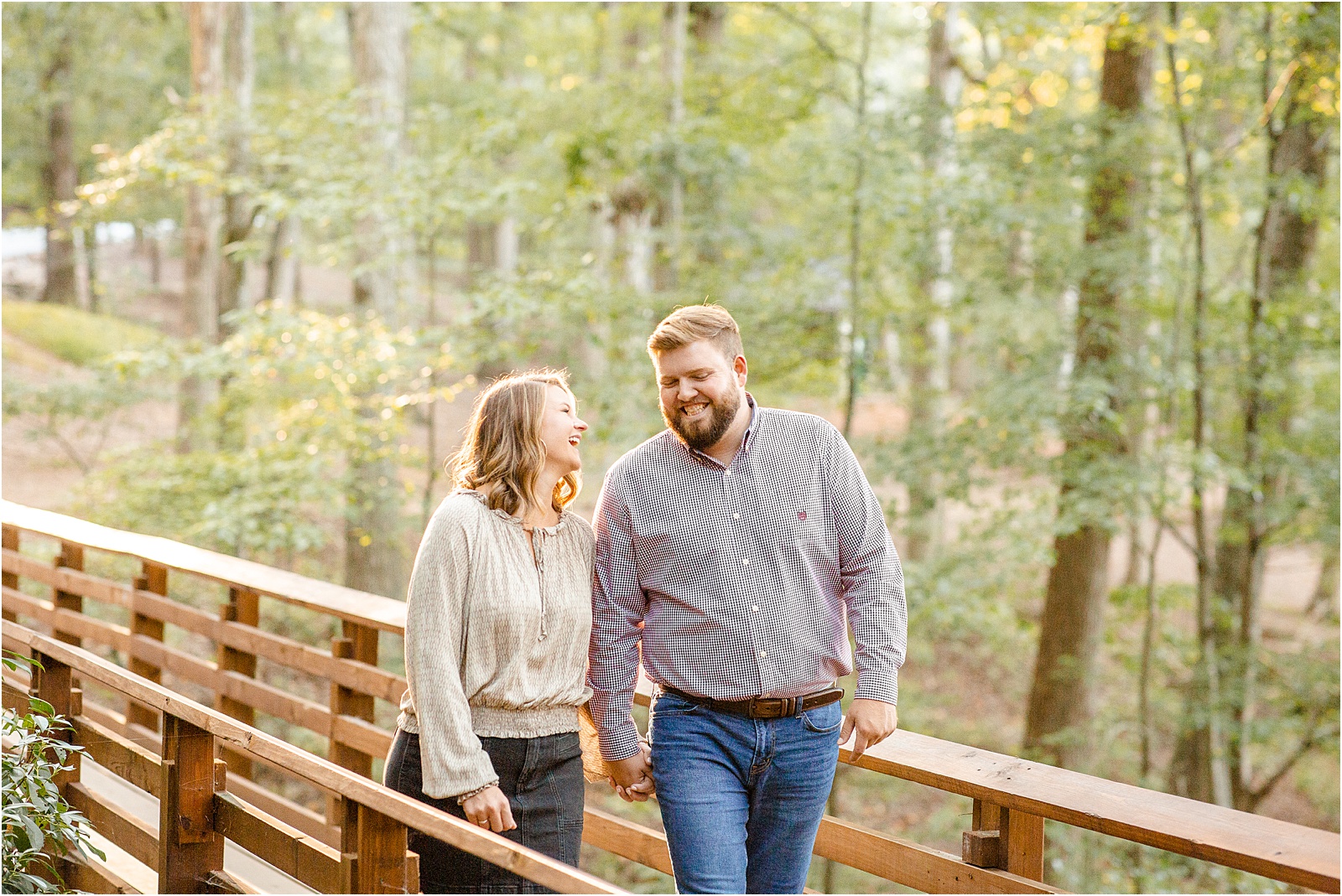 engaged couple laughs as they walk across a bridge at Paris Mountain
