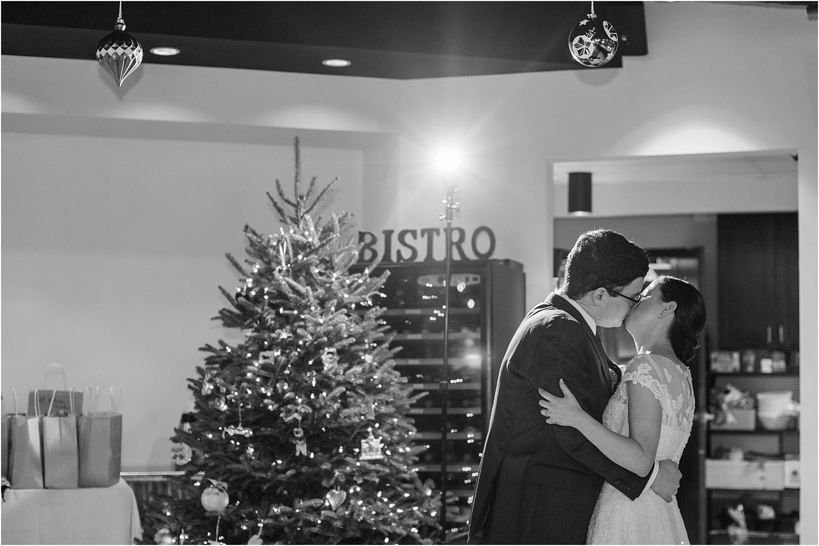 married couple kissing during their first dance with Christmas tree behind them