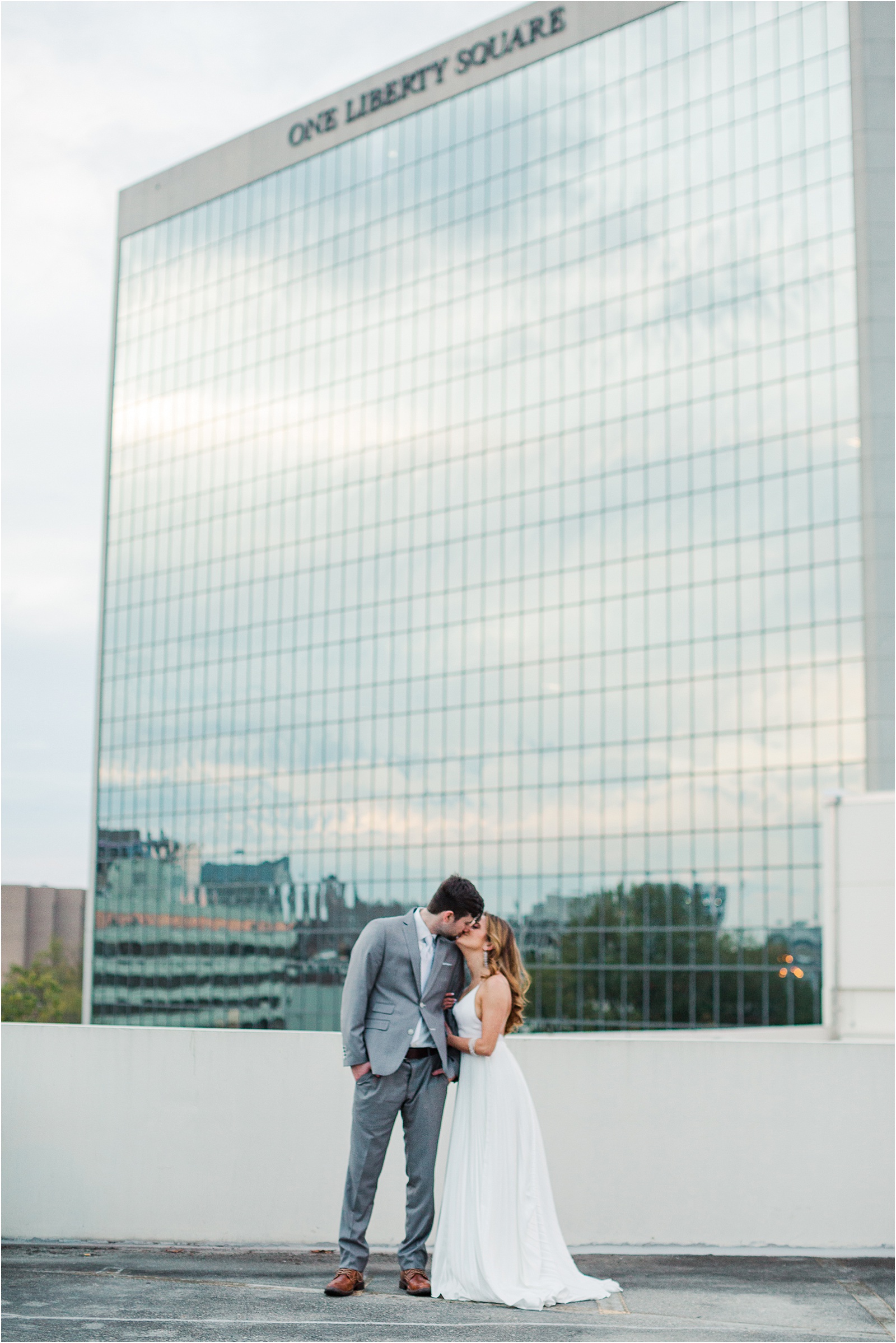 bride and groom kiss with commerce club building in background