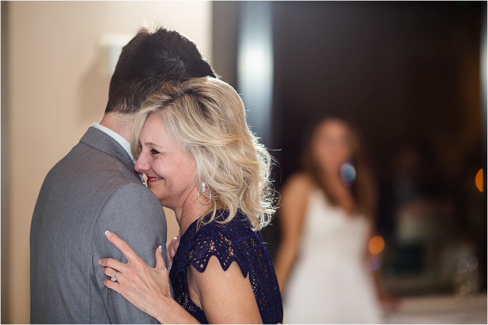 groom dances with mom with bride in the background